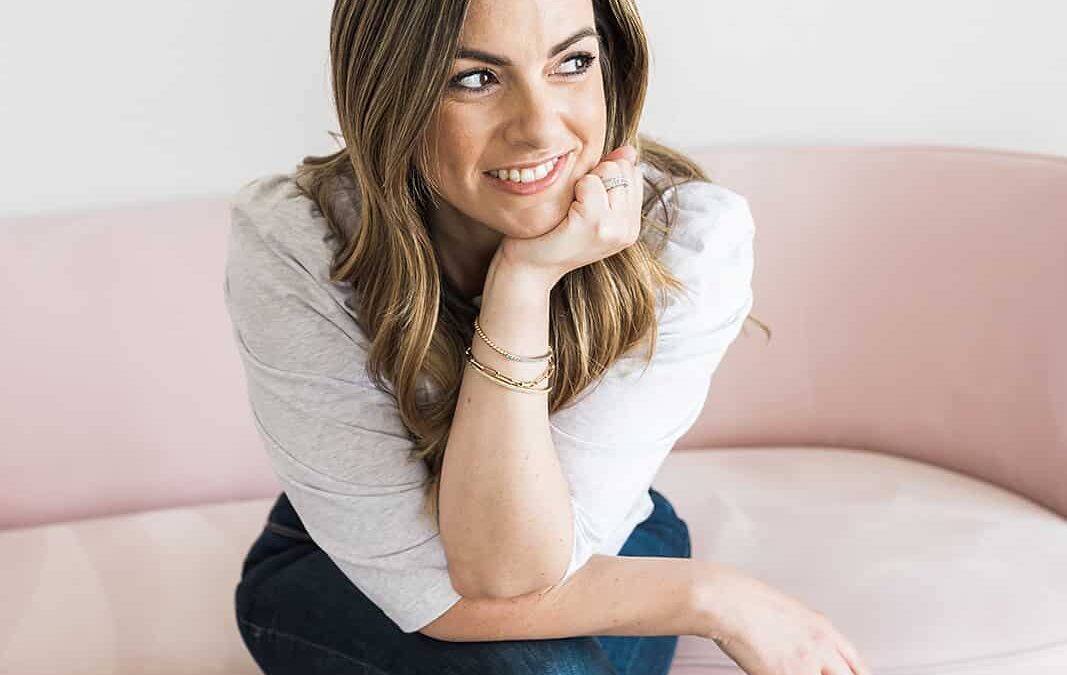 A women sitting cross legged on a couch smiling to the side