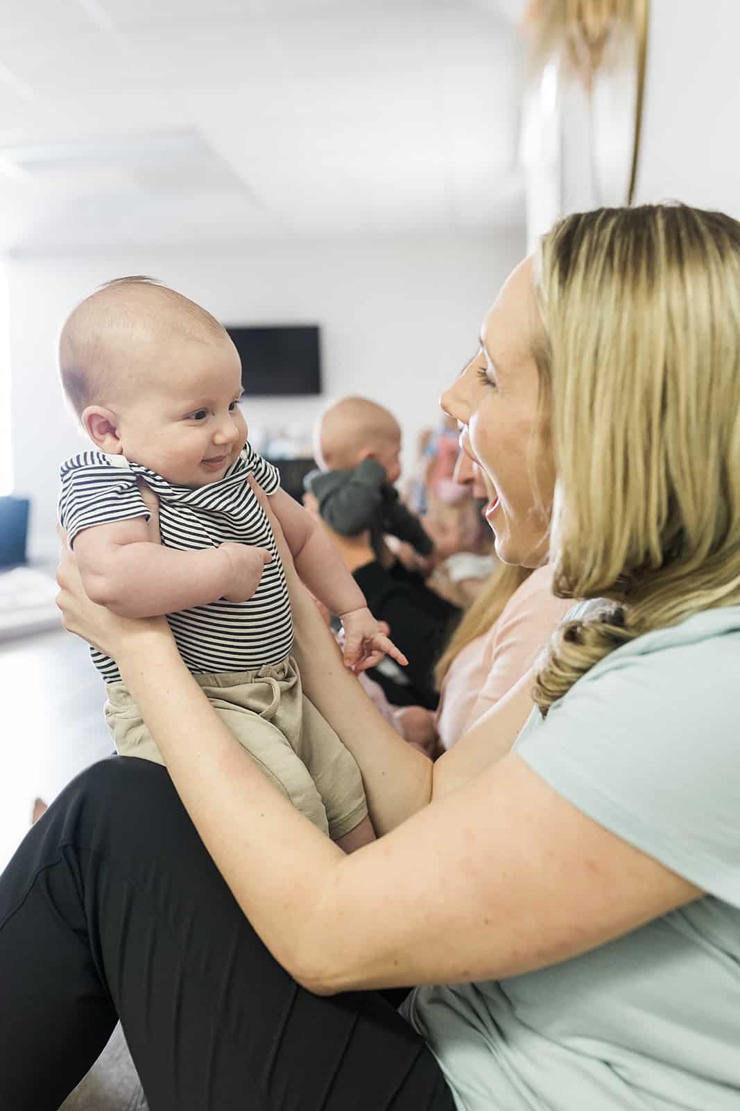 A mother smiling at her baby while she holds him up