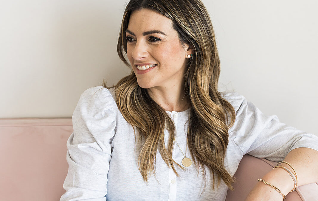 A women sitting on a couch looking to the side and smiling