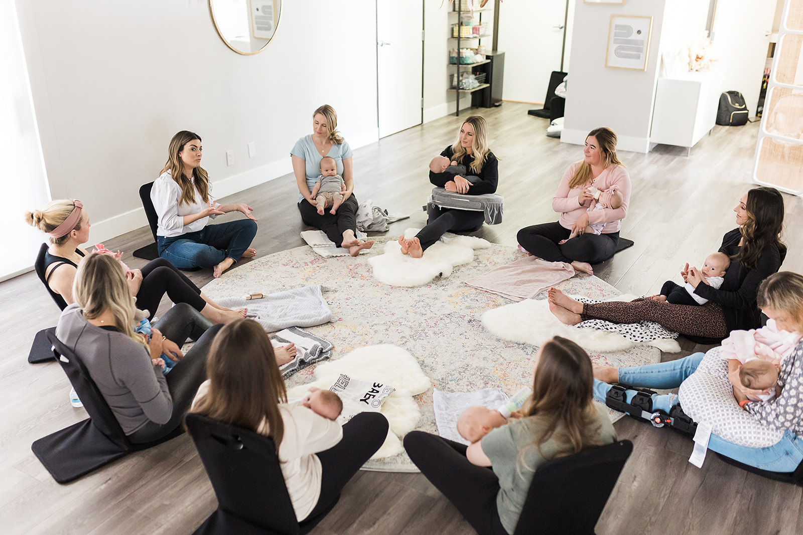 New moms sitting in a circle on the floor holding their babies
