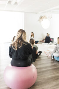 A woman sitting on a yoga ball from behind