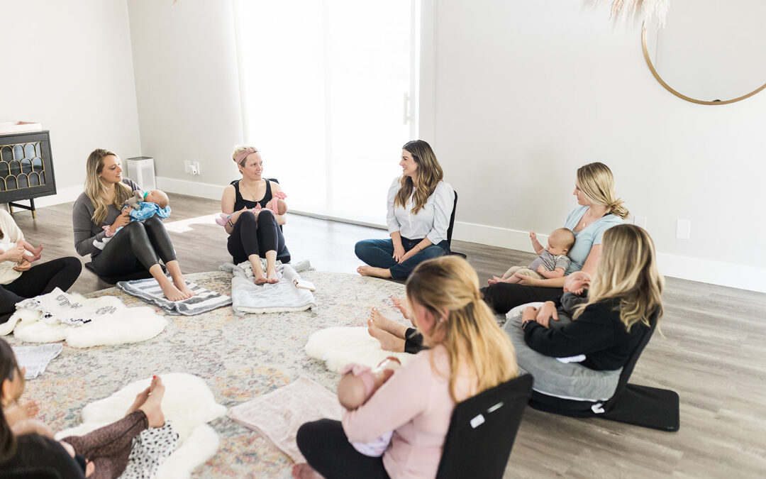 A group of new moms sitting on the floor in a circle with their babies