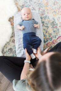 A baby laying on the floor with his feet being held