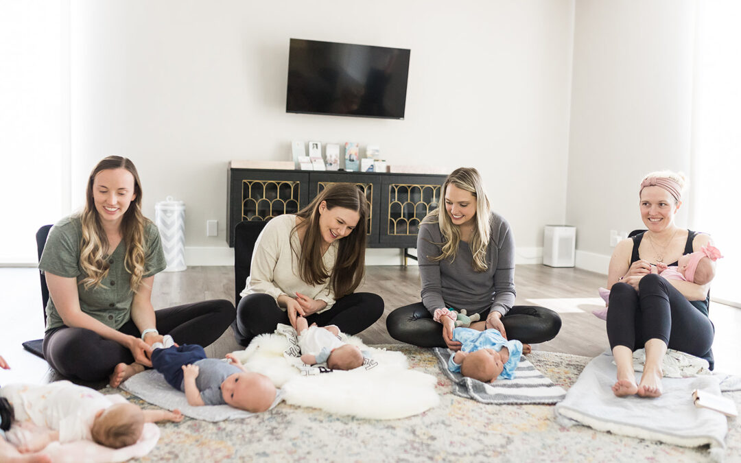 A group of new moms sitting together playing with their babies on the floor