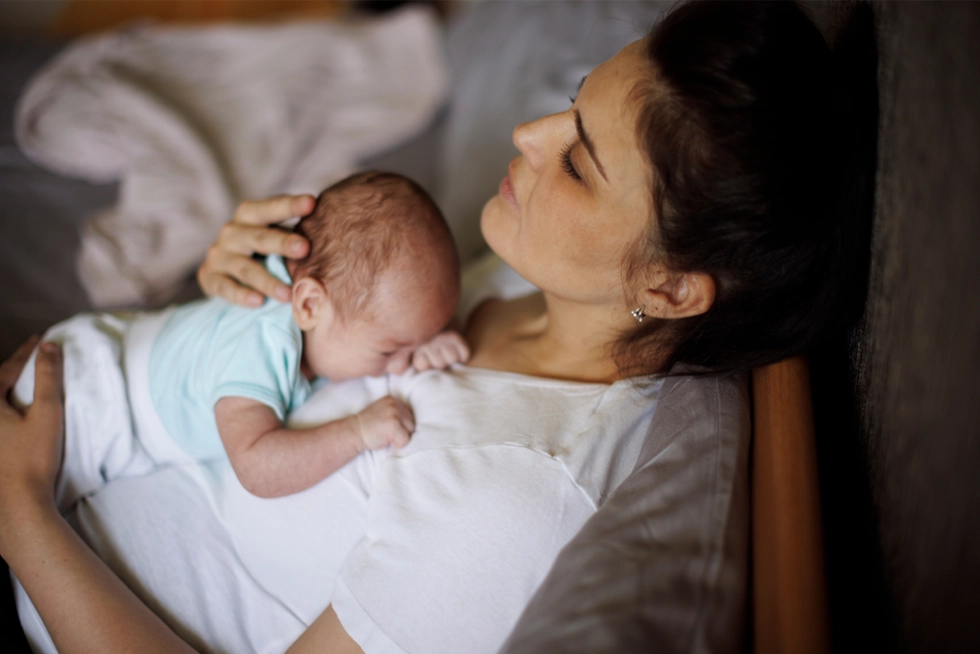 New mom sitting quietly with baby, reflecting on postpartum emotions.