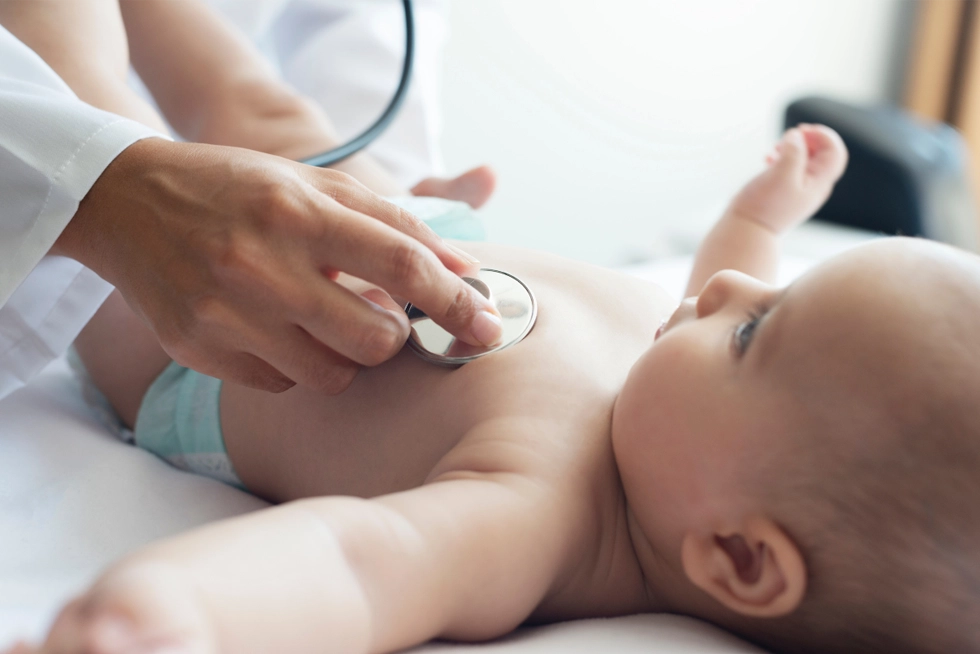 Smiling pediatrician examining baby during a wellness check in Greenville, SC.