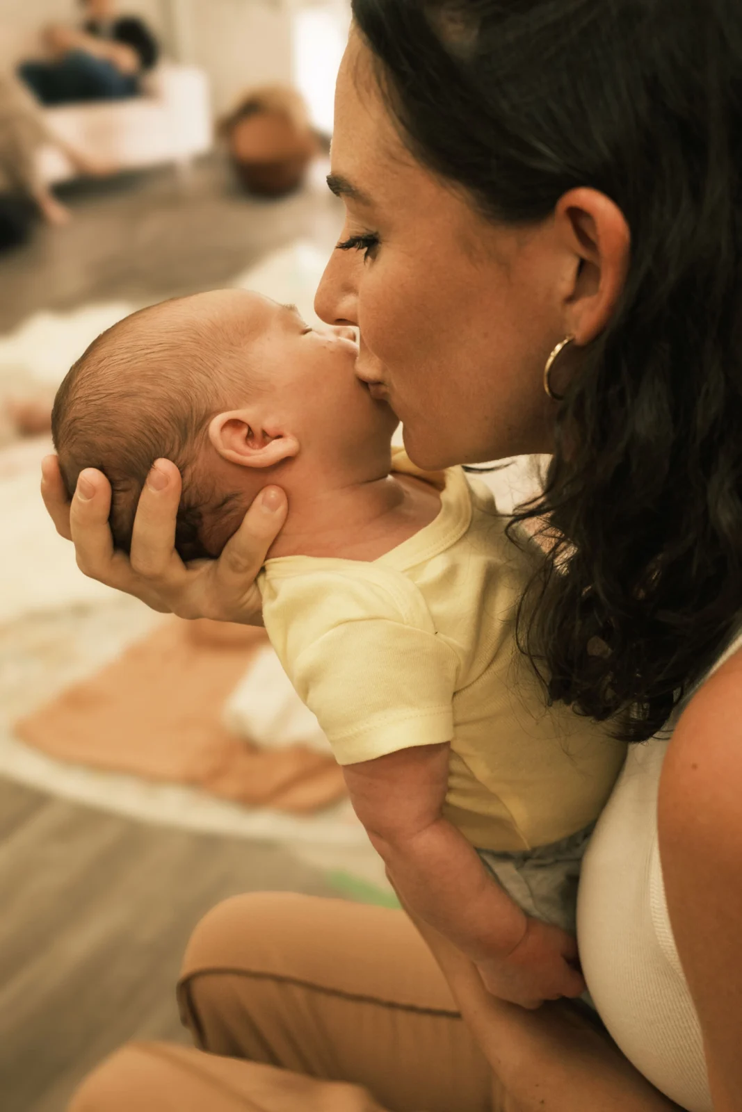 Close-up of a mother gently kissing her newborn on the cheek while cradling their head, capturing a tender and intimate connection.