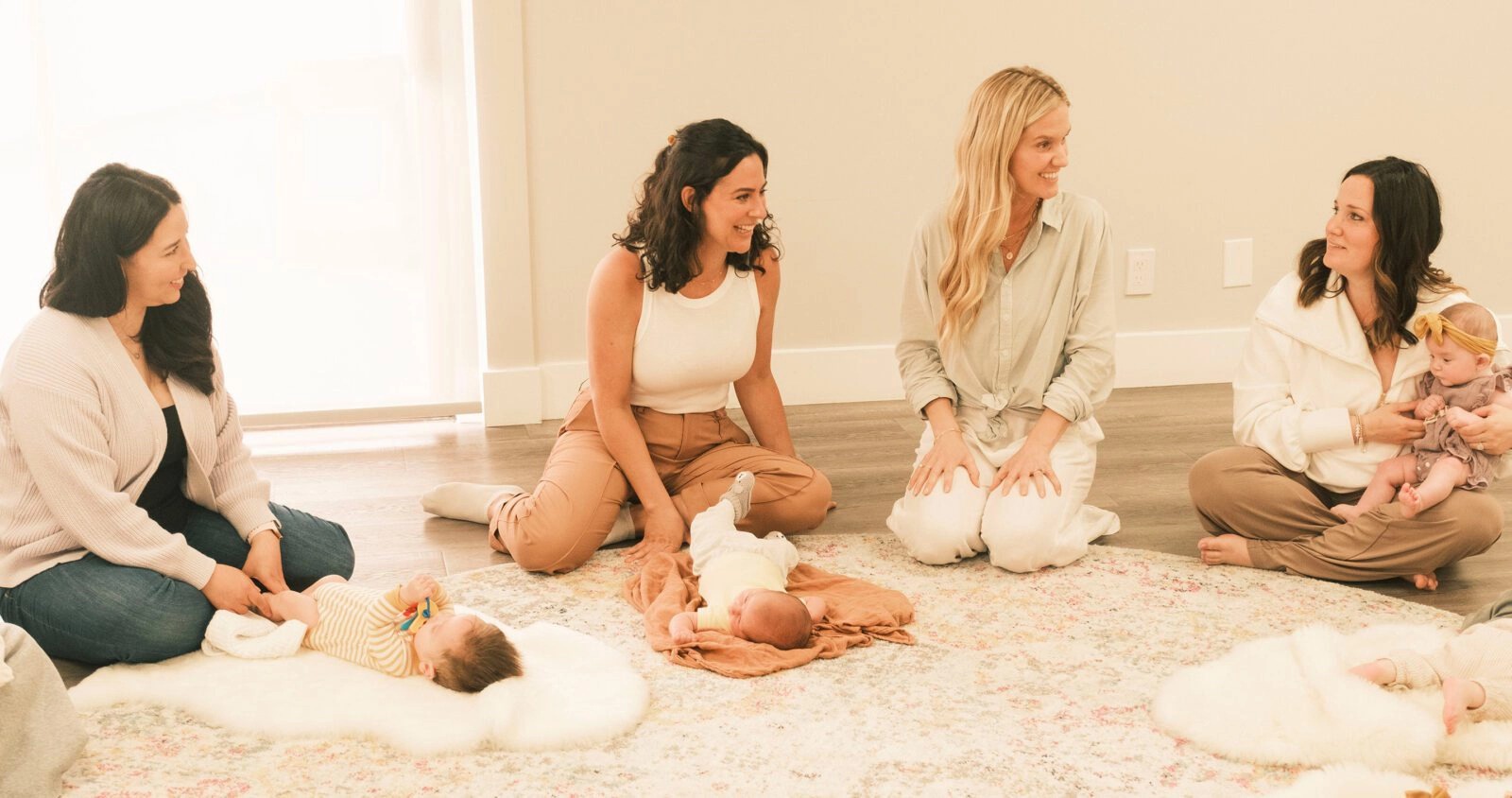 Mothers sitting in a New Mom School classroom setting with their babies during a group session.