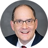 Dr. William Adelman – New Mom School Endorsement Headshot of Dr. William Adelman, wearing glasses and a suit, featured in a New Mom School endorsement or testimonial