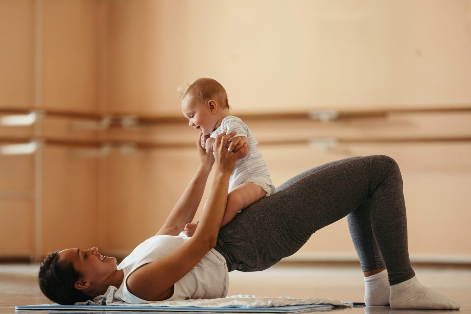 Young mom doing physical therapy while holding her new baby