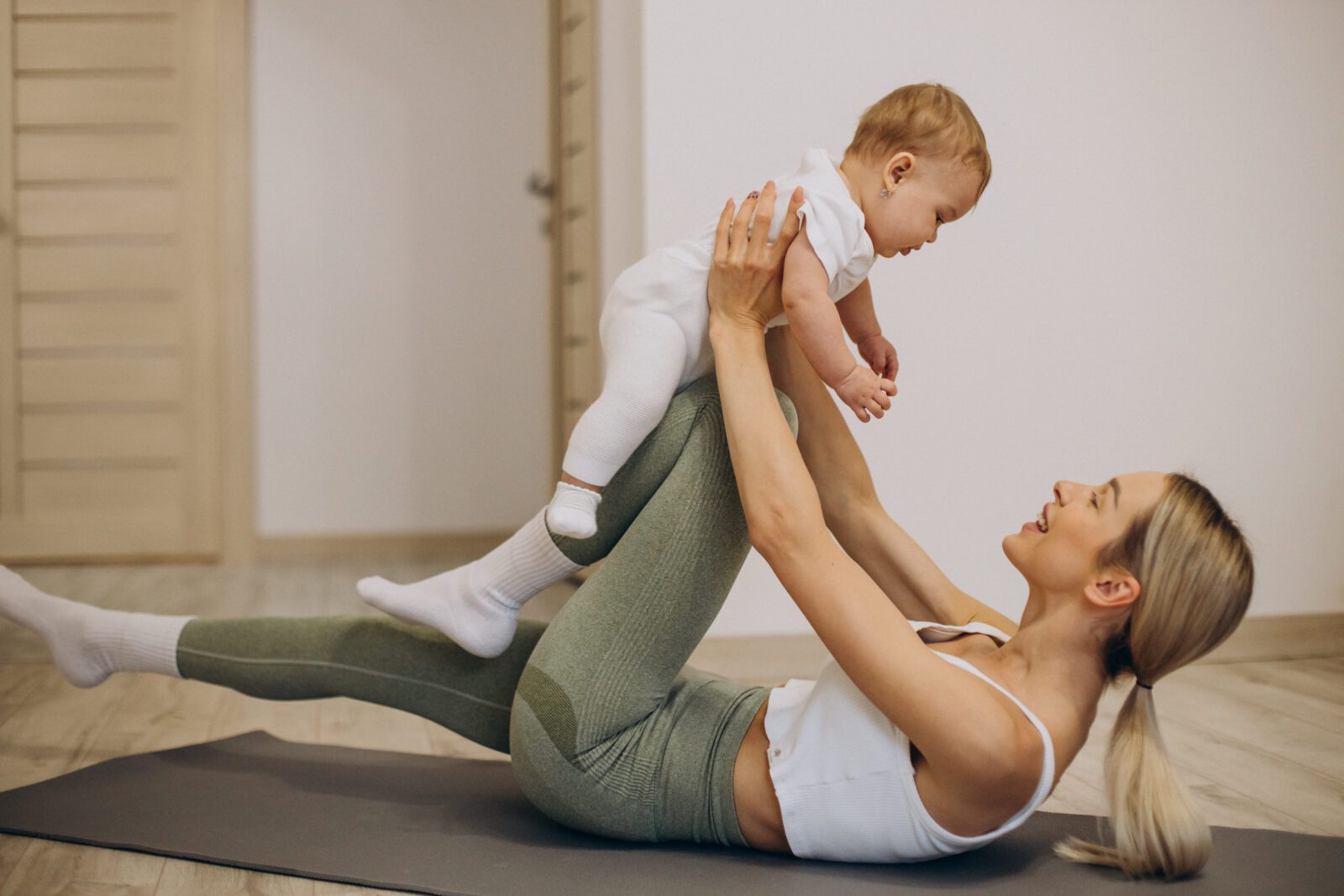 Mother practicing yoga with her baby daughter at home mom doing physical therapy with new baby