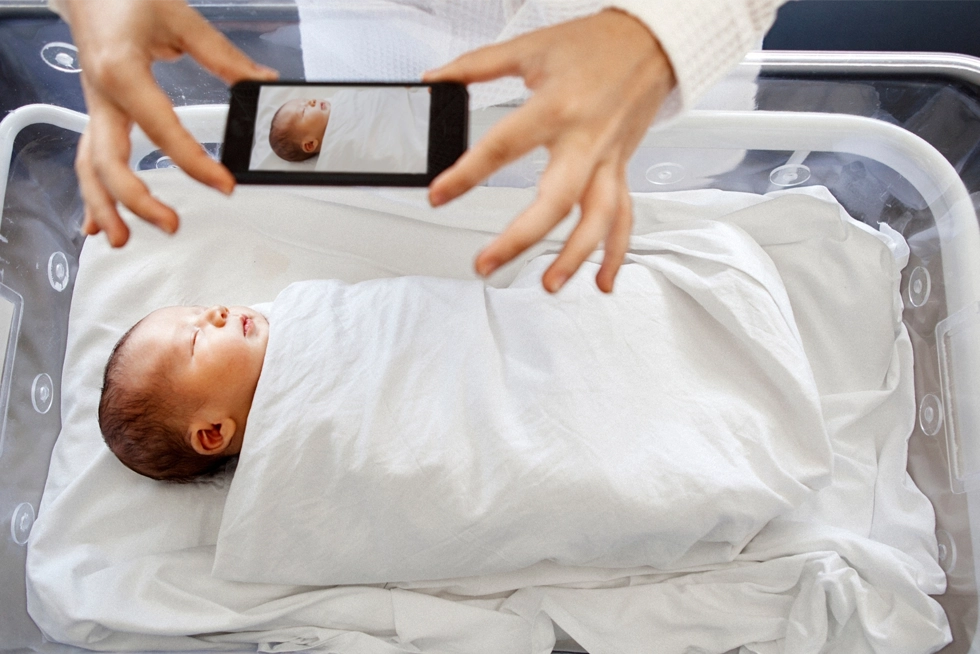 Top Newborn Photographers in Ballantyne NC Parent taking a newborn photo with a smartphone during the first days after birth in Ballantyne, North Carolina.