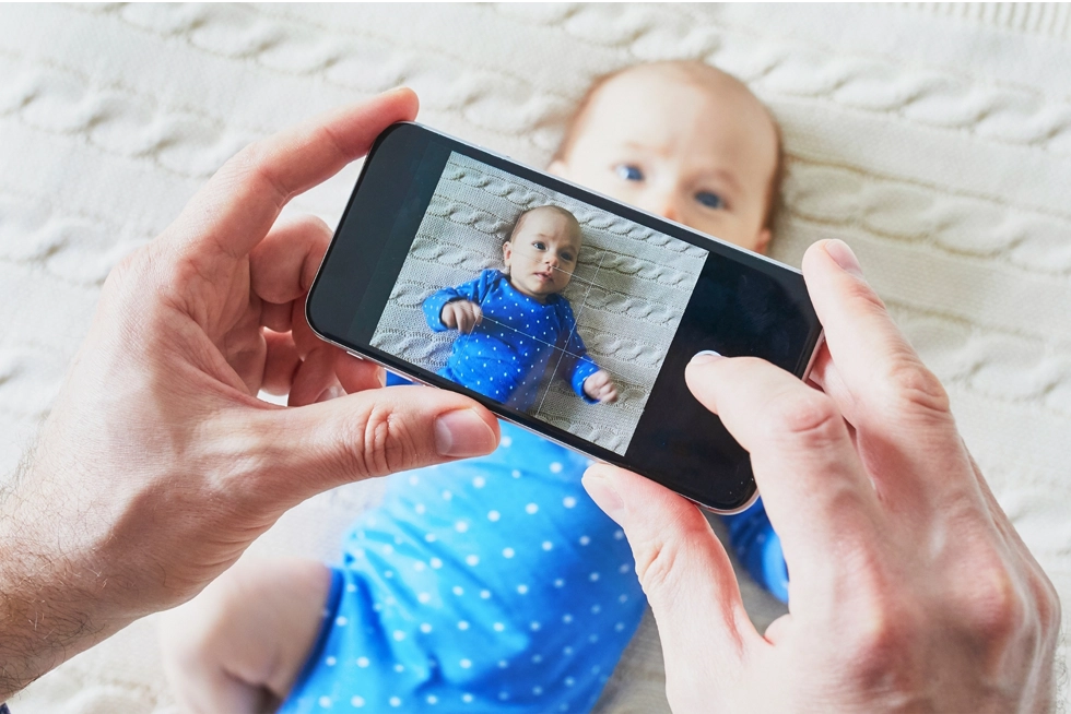 Parent photographing a newborn baby with a smartphone during the first days of life in Charleston, South Carolina.