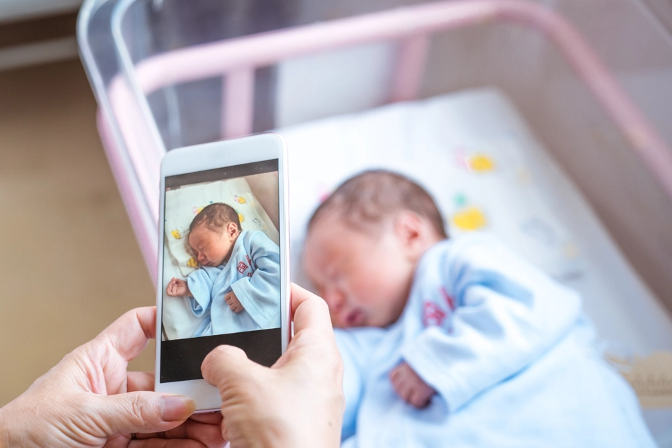 Parent taking a photo of a newborn baby in a hospital bassinet shortly after birth in Katy, Texas.