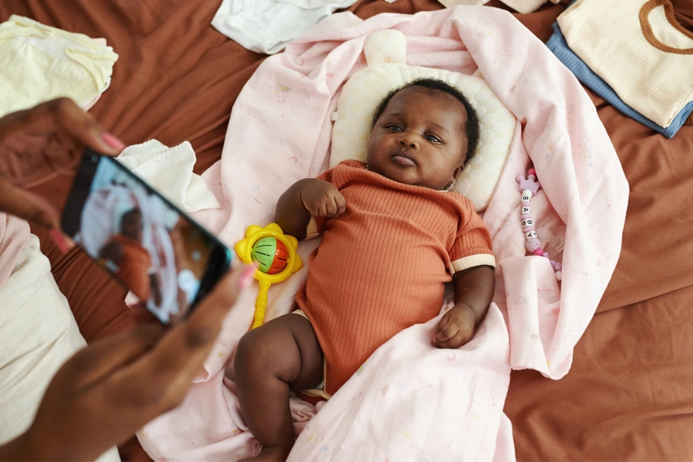 Parent taking a photo of a newborn baby during an at-home newborn photography session in Philadelphia, Pennsylvania.